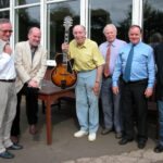 Group of men celebrating a birthday with one holding a guitar.